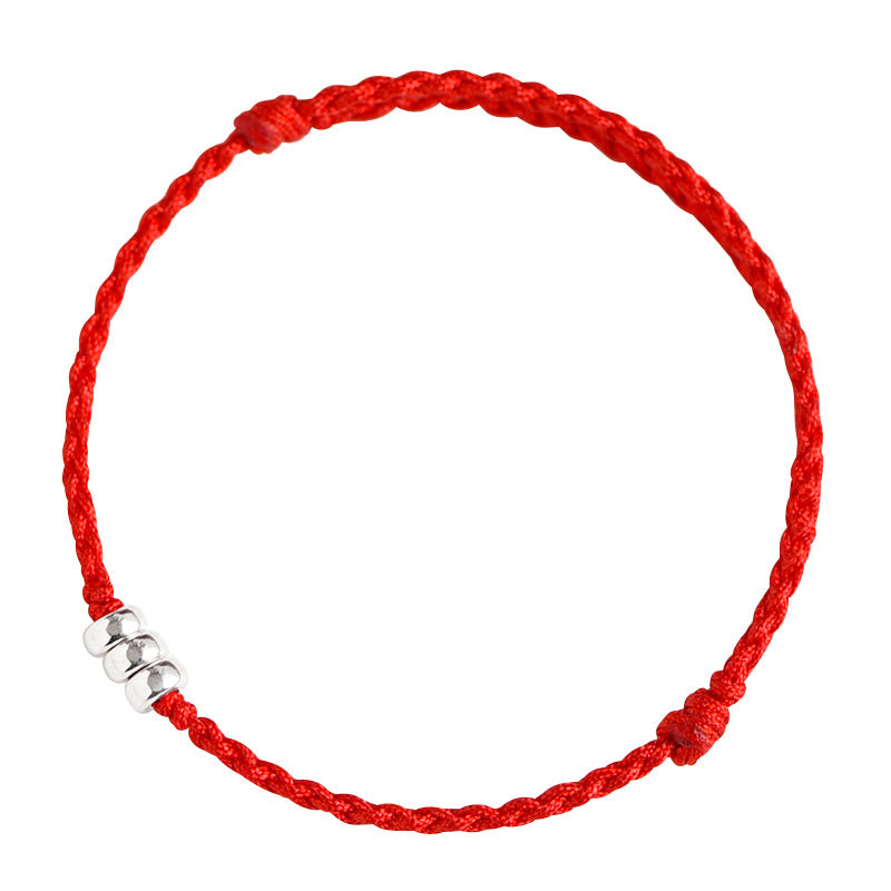 Red woven lucky bracelet with silver beads on solid red background, artistic flat lay