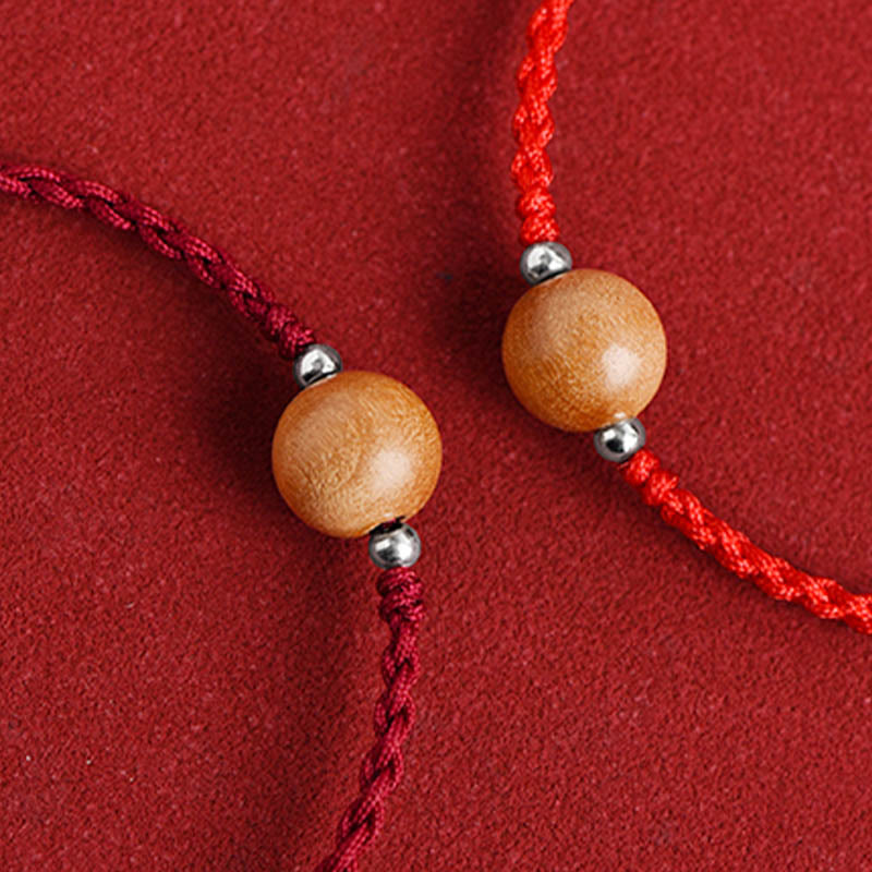 Pair of peach wood bead bracelets - one dark red cord, one bright red cord with wood and silver details