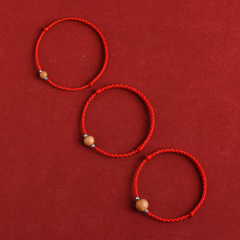 Three small red braided peach wood bead bracelets - flat lay showing different bead sizes