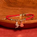 2025 Year of the Snake Fu character red string bracelet main view on wooden tray red fabric background
