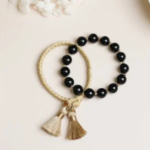 2pcs black onyx tassel string bracelet set flat lay on light background