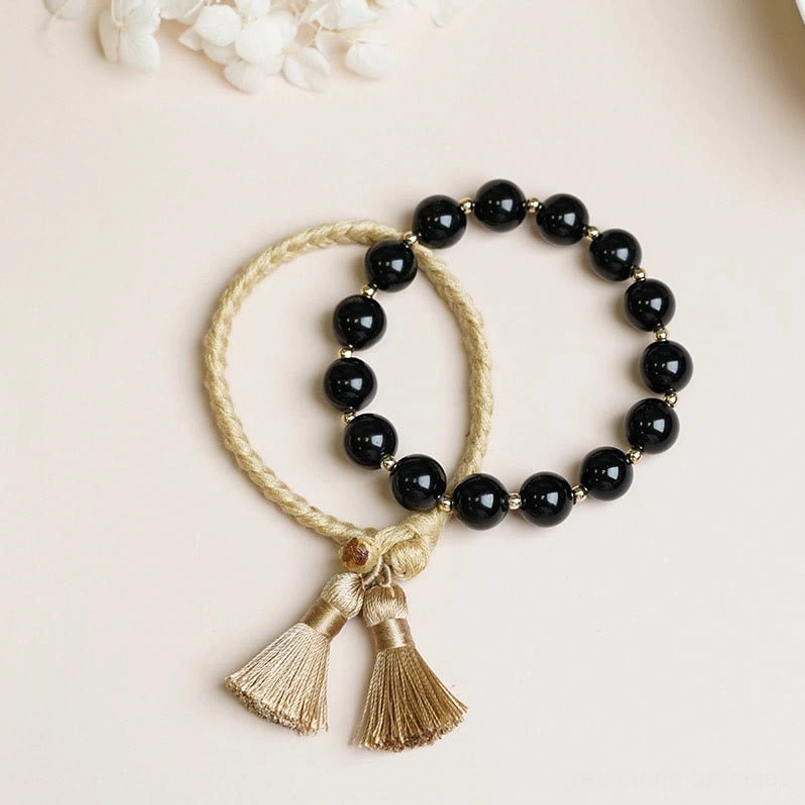 2pcs black onyx tassel string bracelet set flat lay on light background