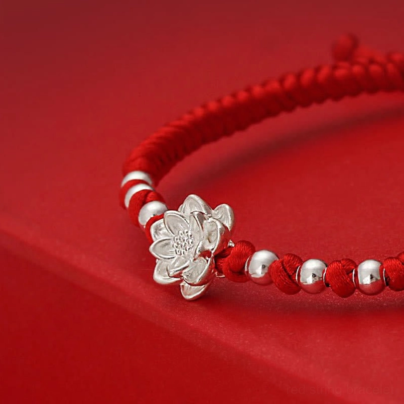 Close up view of 3D 999 sterling silver lotus charm on braided red string bracelet