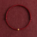 999 gold bead red string braided bracelet flat lay top-down view