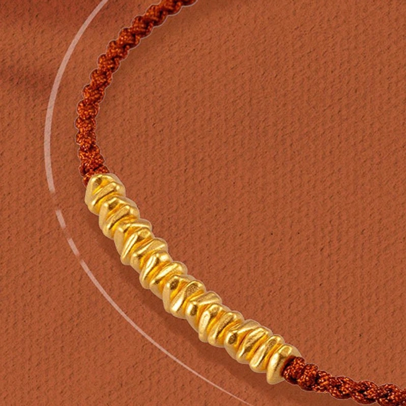 close up of 999 gold small pieces on red braided string bracelet