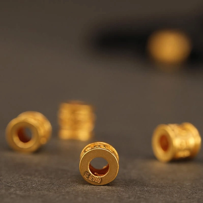 Close up of 999 gold engraved barrel beads marked 999 gold