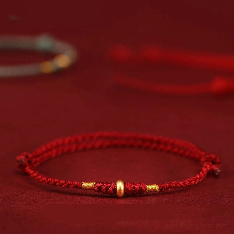 999 gold lucky bead red string bracelet side close-up with wine red background