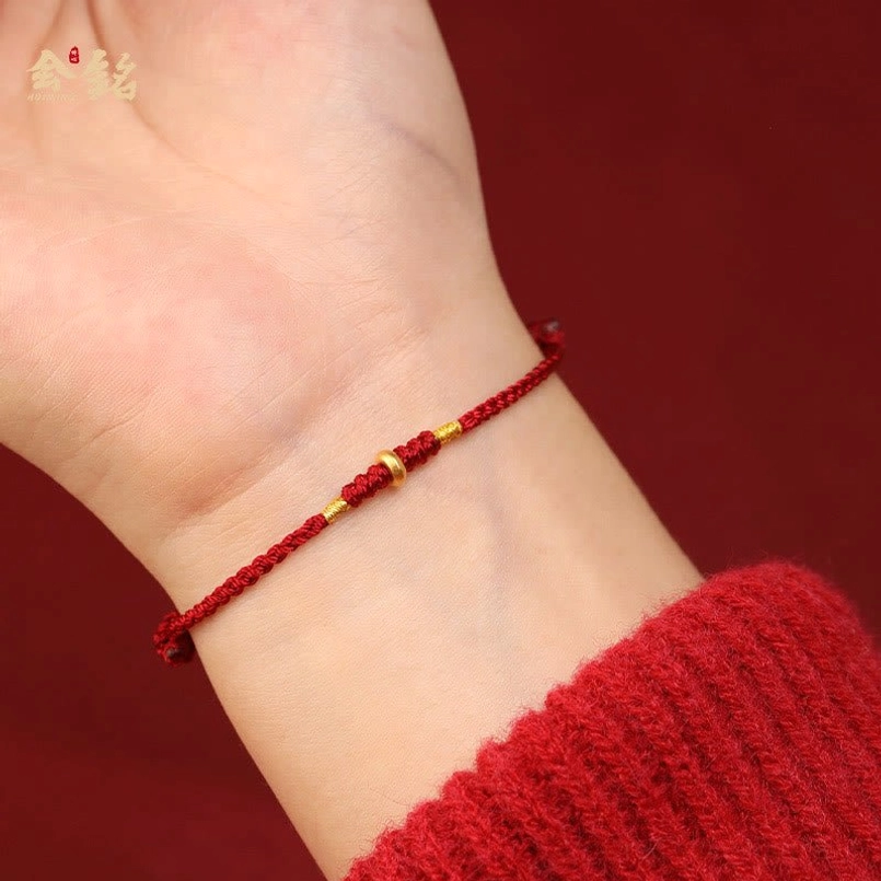 Red string bracelet worn on wrist showing real wearing effect and gold bead design