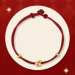 999 gold lucky rabbit red string bracelet flat lay on red diamond backdrop