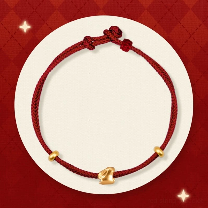 999 gold lucky rabbit red string bracelet flat lay on red diamond backdrop