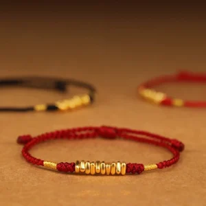999 gold red string protection bracelet overhead flat lay multiple beads