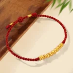999 gold small pieces handmade red string protection bracelet flat lay on wooden table