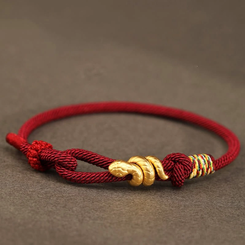 999 gold year of the snake red string bracelet side upper view dark gray background