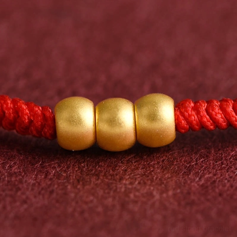 Detail view of barrel shaped 999 gold beads on red luck bracelet