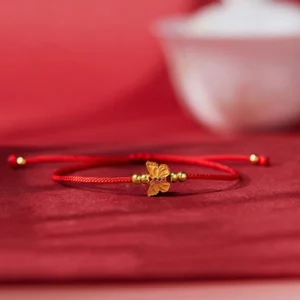 999 sterling silver butterfly red string bracelet side overhead view on red satin background