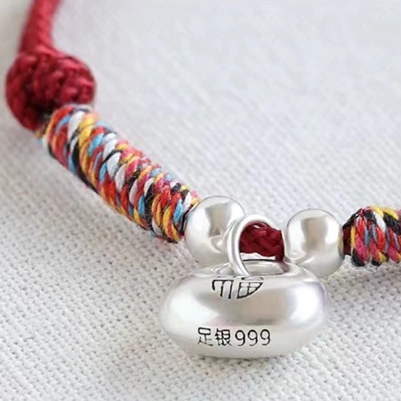 Extreme close up of 999 silver Fu charm and multicolor woven red bracelet section