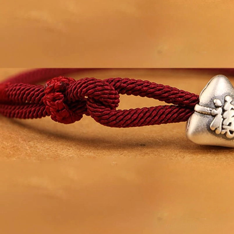 Close up of polished 999 sterling silver fu zongzi charm on red string