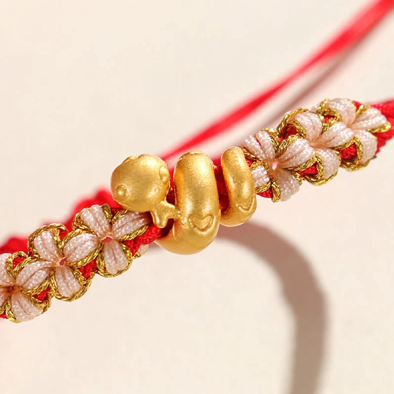 Macro close up of 3D sterling silver snake charm on red string bracelet
