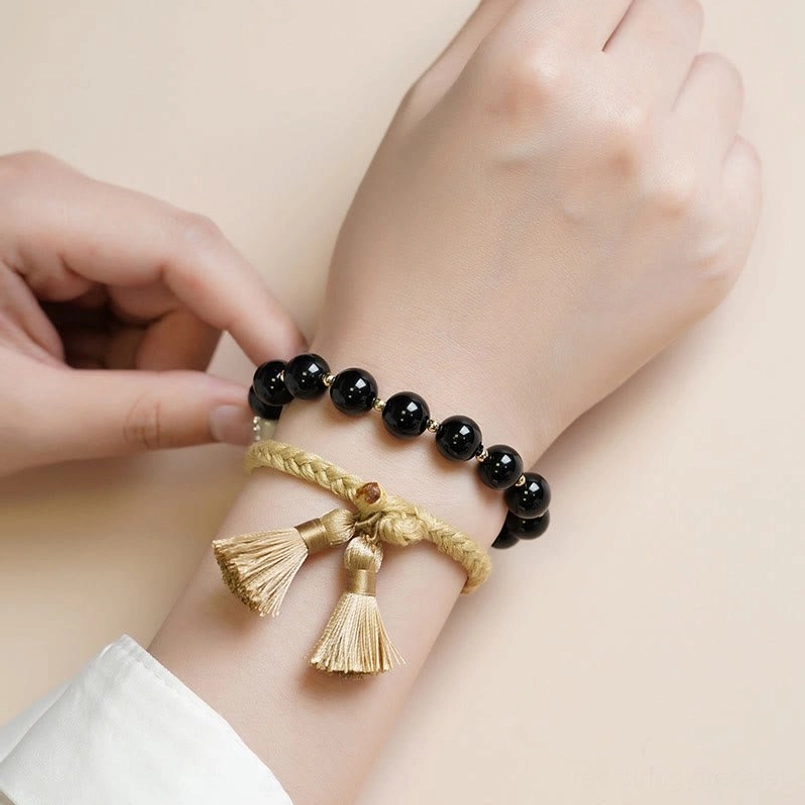 adjustable black onyx tassel bracelet being put on hand