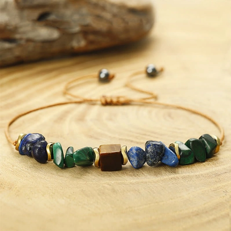 Adjustable malachite tiger's eye lapis lazuli bracelet with wax cord and sliding adjuster on wood background