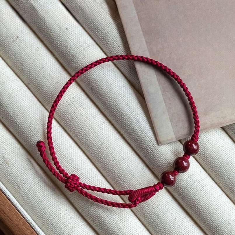 Adjustable cinnabar bead red string bracelet flat lay display