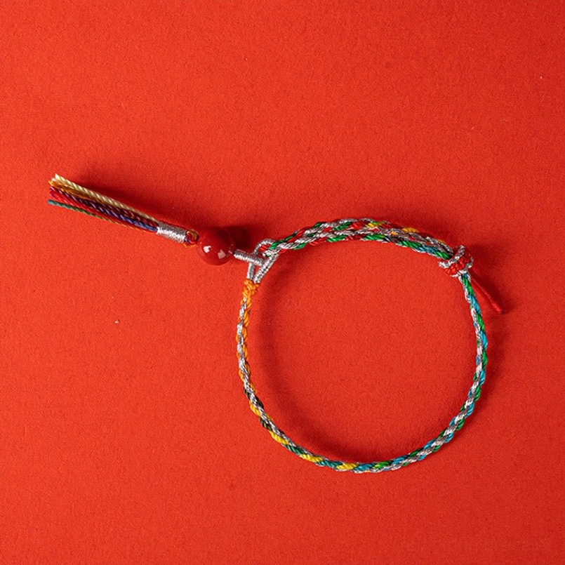 Adjustable knot colorful cinnabar bracelet on solid red backdrop