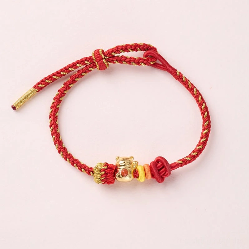 Flat overhead view of adjustable copper cat red string luck bracelet on off white background
