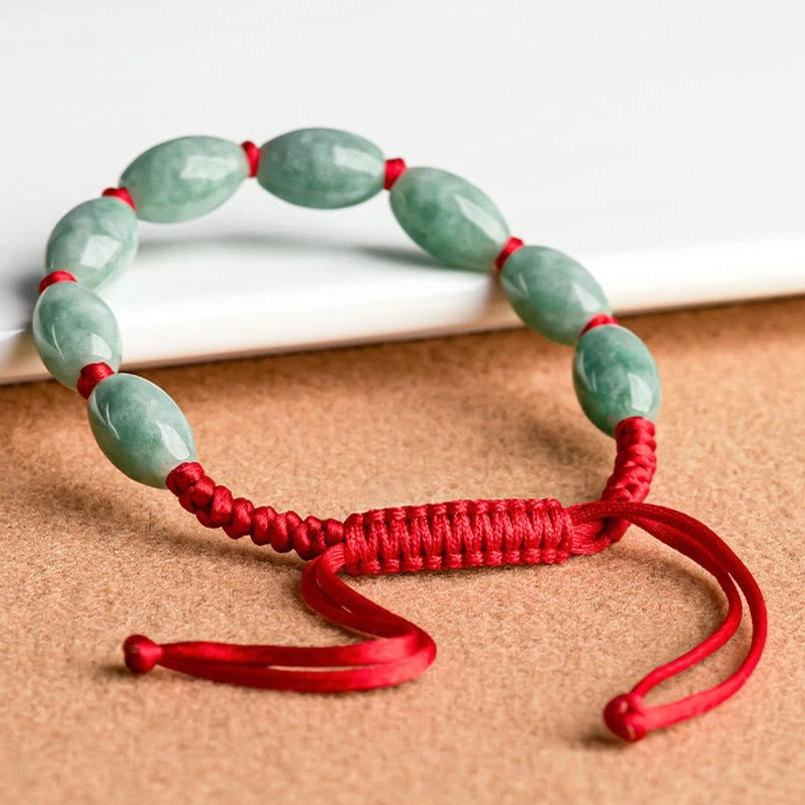Side flat lay of jade red string bracelet showing long adjustable cord tails