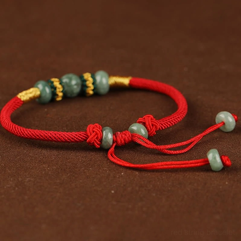 Adjustable jade red string bracelet top down flat lay on dark brown background