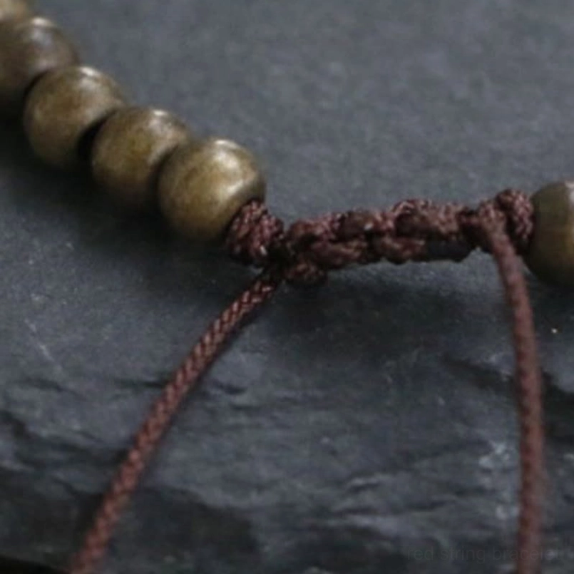 Close-up of braided cord pull-tie closure on red string copper bead bracelet