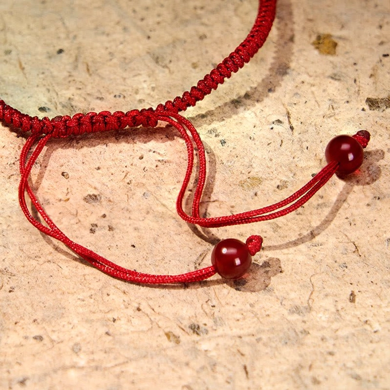 Adjustable red agate bracelet fastener showing woven braided cord and pull adjuster design