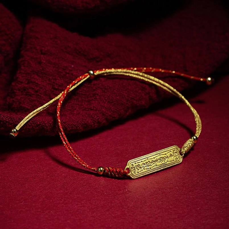 Adjustable red gold amulet bracelet side view on folded red fabric