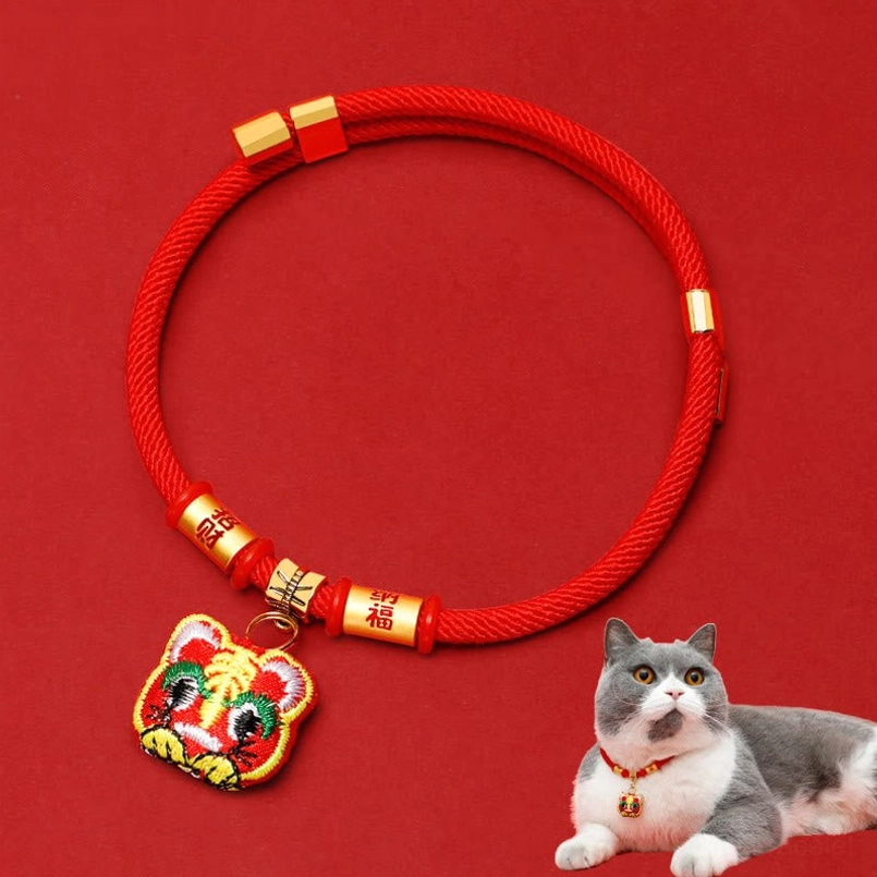Overhead flat lay of adjustable red pet collar with gold fu character beads and embroidered tiger pendant