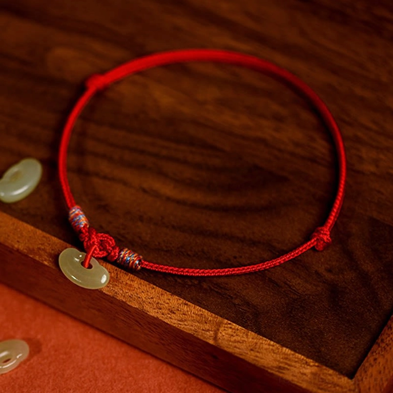 Red adjustable pet collar with colored woven knots and jade safety pendant, side view