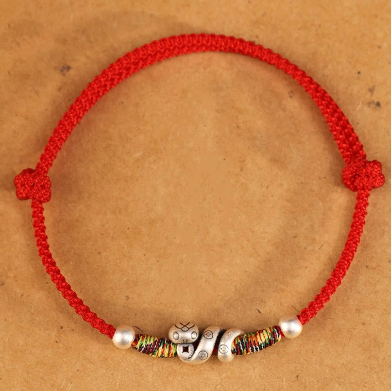 Red string adjustable anklet flat lay showing braided knot design, silver snake charm, colorful woven sections, and round silver spacer beads