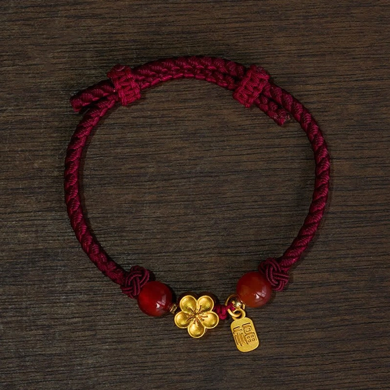 Overhead view of adjustable red string bracelet with engraved fu charm