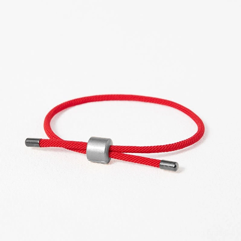 Adjustable red string bracelet silver clasp white background flat lay