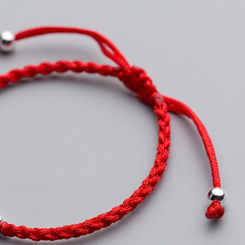 Adjustable red braided cord bracelet with sliding closure knot and silver end caps