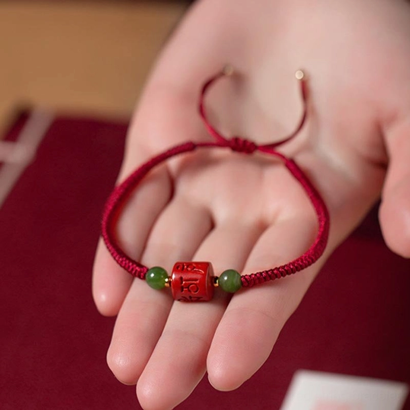 Adjustable red braided Tibetan bracelet with open clasp in palm, cinnabar bead and jade