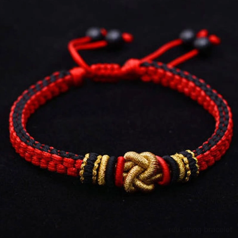 Red black and gold woven string bracelet with adjustable black beads on solid black background