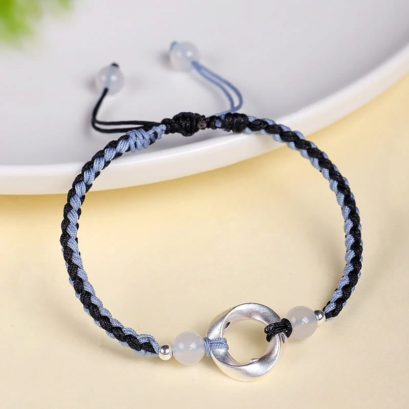 Black and blue braided red string bracelet with white agate and sterling silver charm, eye-level jewelry shot