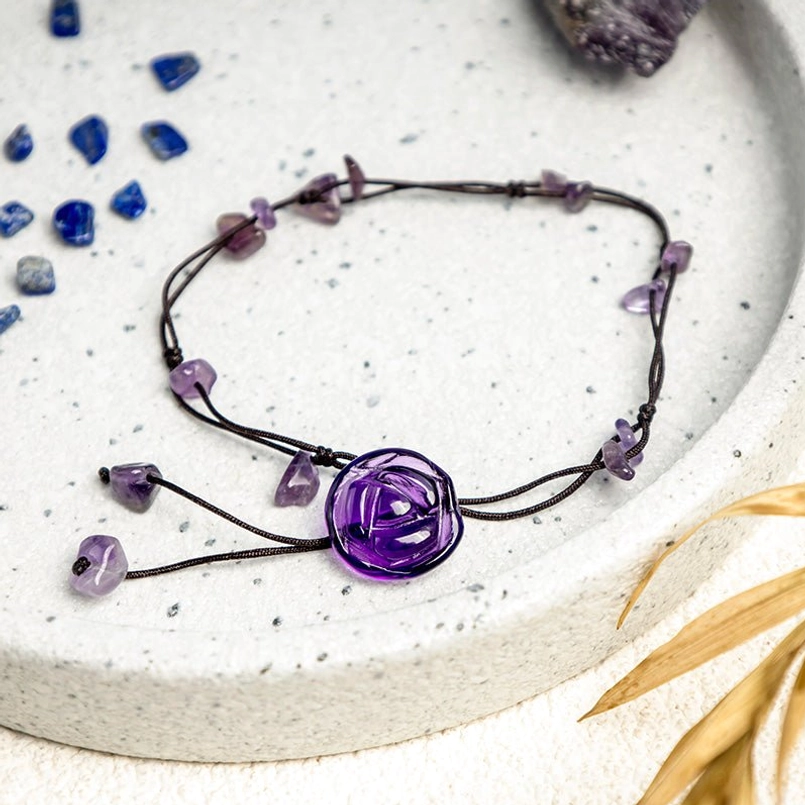 Handmade amethyst crystal anklet with adjustable black cord and dangling amethyst pieces on ceramic tray
