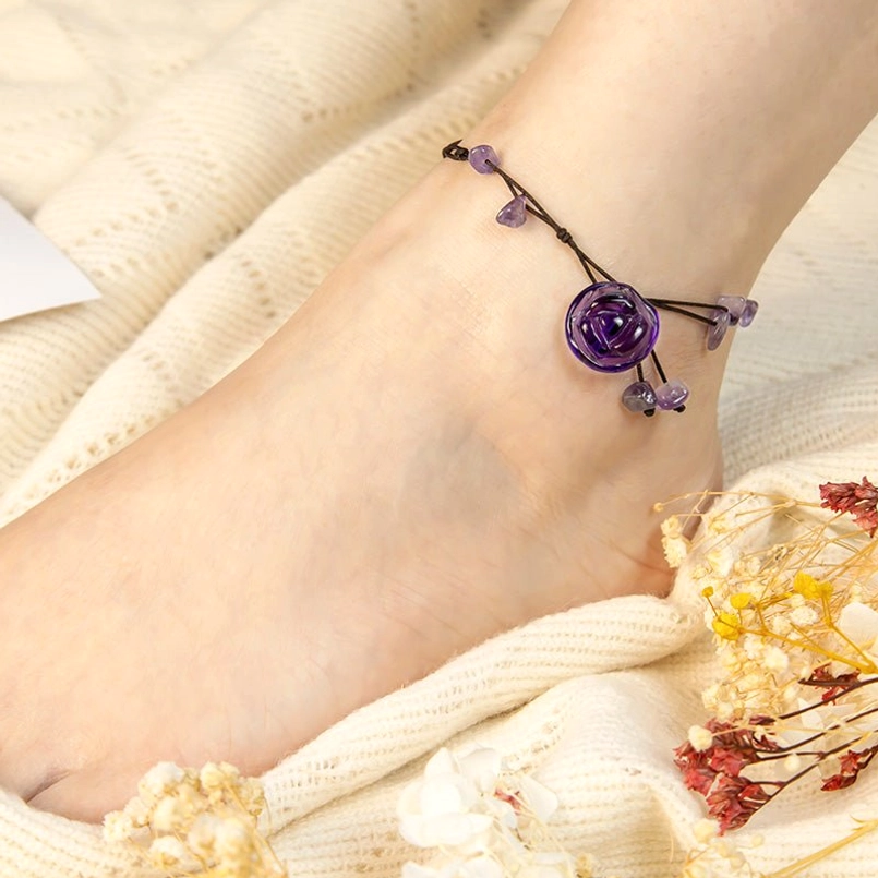 Close-up side view of amethyst crystal anklet with black cord and purple rose pendant