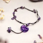 Amethyst healing crystal anklet with purple rose pendant and amethyst chips on light background with dried flowers