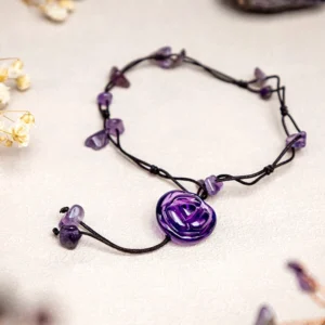 Amethyst healing crystal anklet with purple rose pendant and amethyst chips on light background with dried flowers