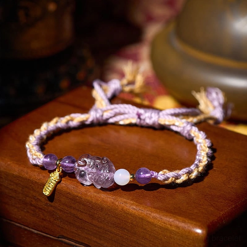 Side close up of amethyst Pixiu red string bracelet with engraved gold metal tag