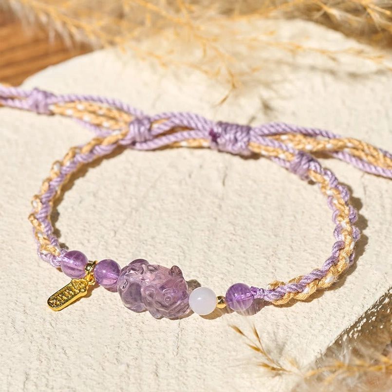 Flat lay top view of amethyst Pixiu lucky bracelet on linen with pampas grass