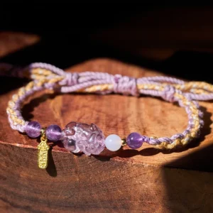 Amethyst Pixiu lucky red string bracelet close up on wooden display block