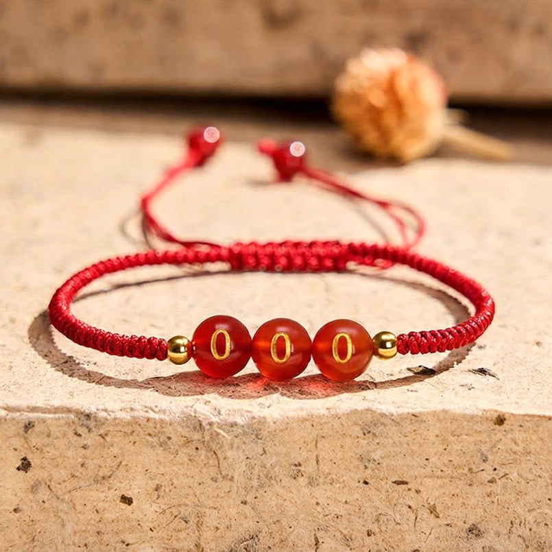 Angel Number 000 Red Agate Bracelet with engraved zero beads on stone table with dried flowers
