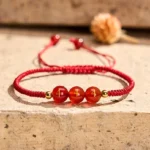 Angel Number 444 Red Agate Bracelet with engraved beads and gold spacers on stone surface